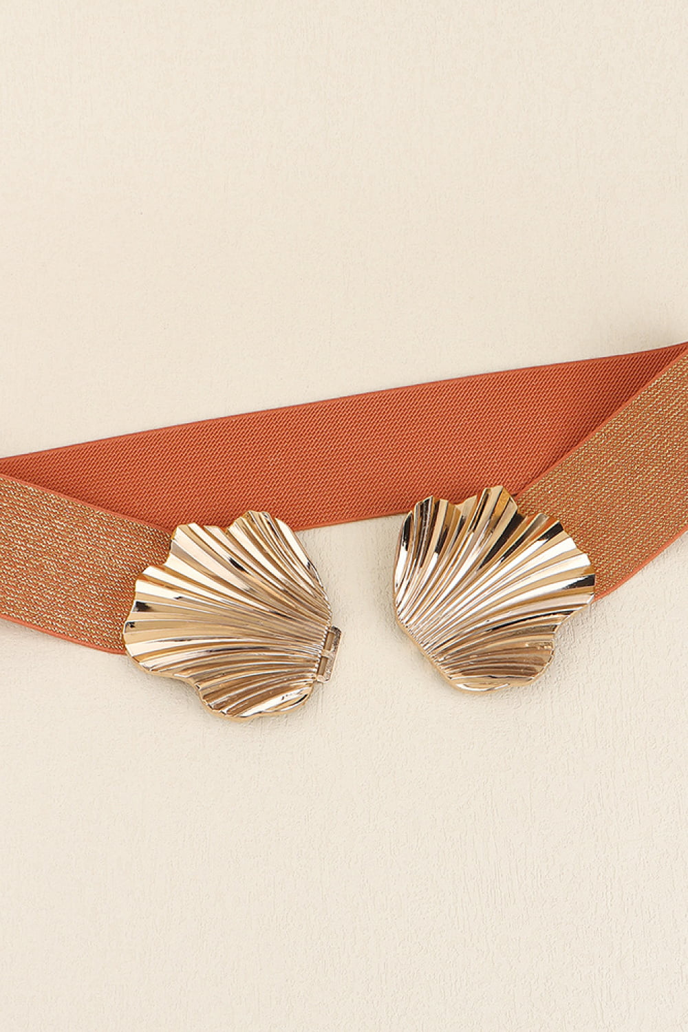 Elastic belt with gold seashell buckle detail and textured strap.