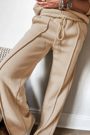 Tan seamed jogger pants with drawstring waist and cuffed ankles.