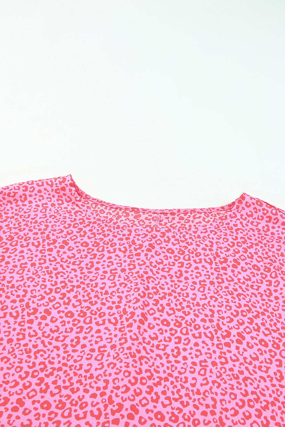 Pink leopard print blouse with smocked sleeves and a round neckline.