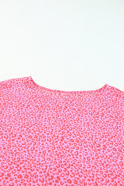 Pink leopard print blouse with smocked sleeves and a round neckline.