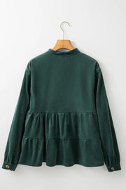 Dark green corduroy tiered button-up blouse with long sleeves and button cuffs.