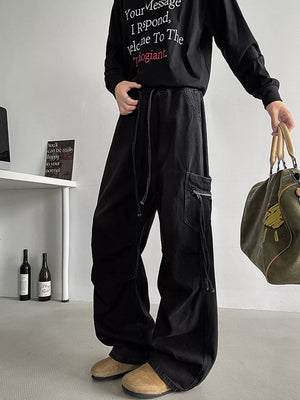 Black relaxed fit cargo jeans with drawstring waist and zippered pocket detail.