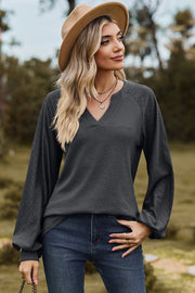 Dark Gray waffle knit raglan v-neck top with textured sleeves and a notched neckline.