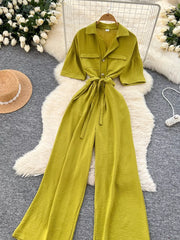 Belted wide-leg jumpsuit in green with short sleeves, collared neckline, and button details.