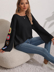 Black knit sweater with colorful granny square crochet sleeve details and bell sleeves.