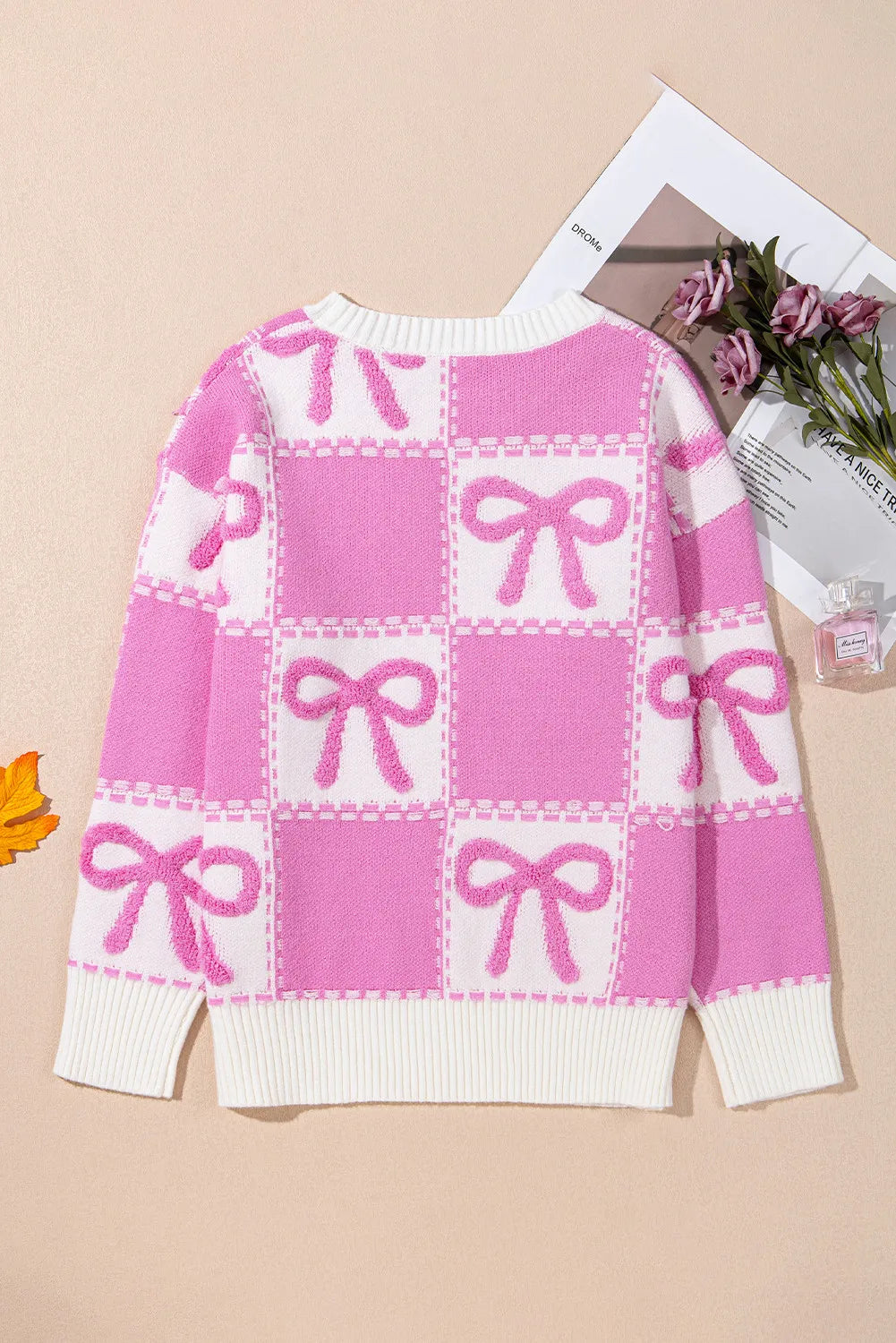 Fuchsia pink and white checkered bow jacquard knit sweater with crew neck and ribbed trim.