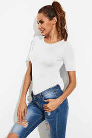 White crew-neck jersey bodysuit with short sleeves, styled with ripped jeans.