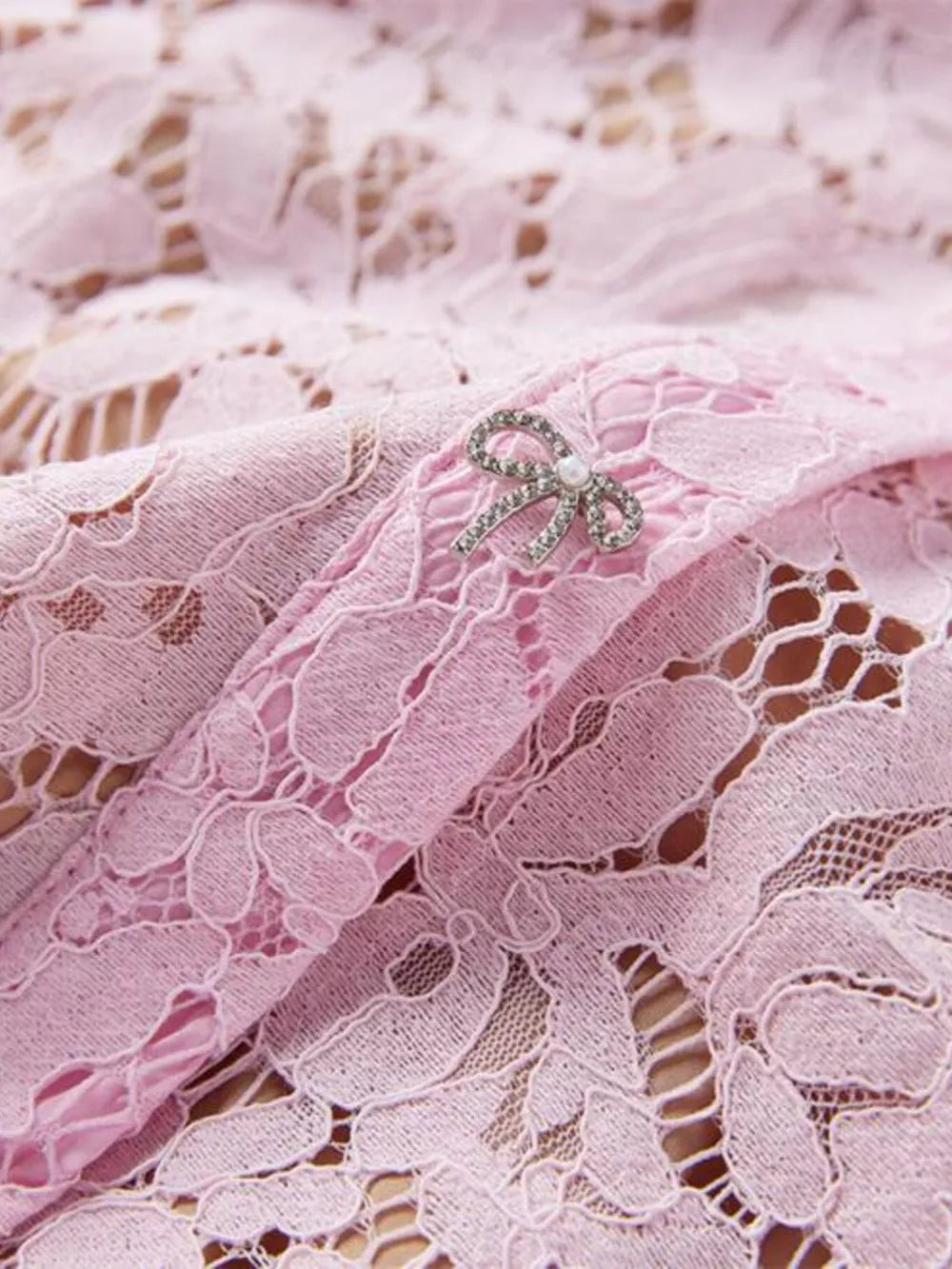 Powder floral lace mermaid dress detail with rhinestone bow belt accent.