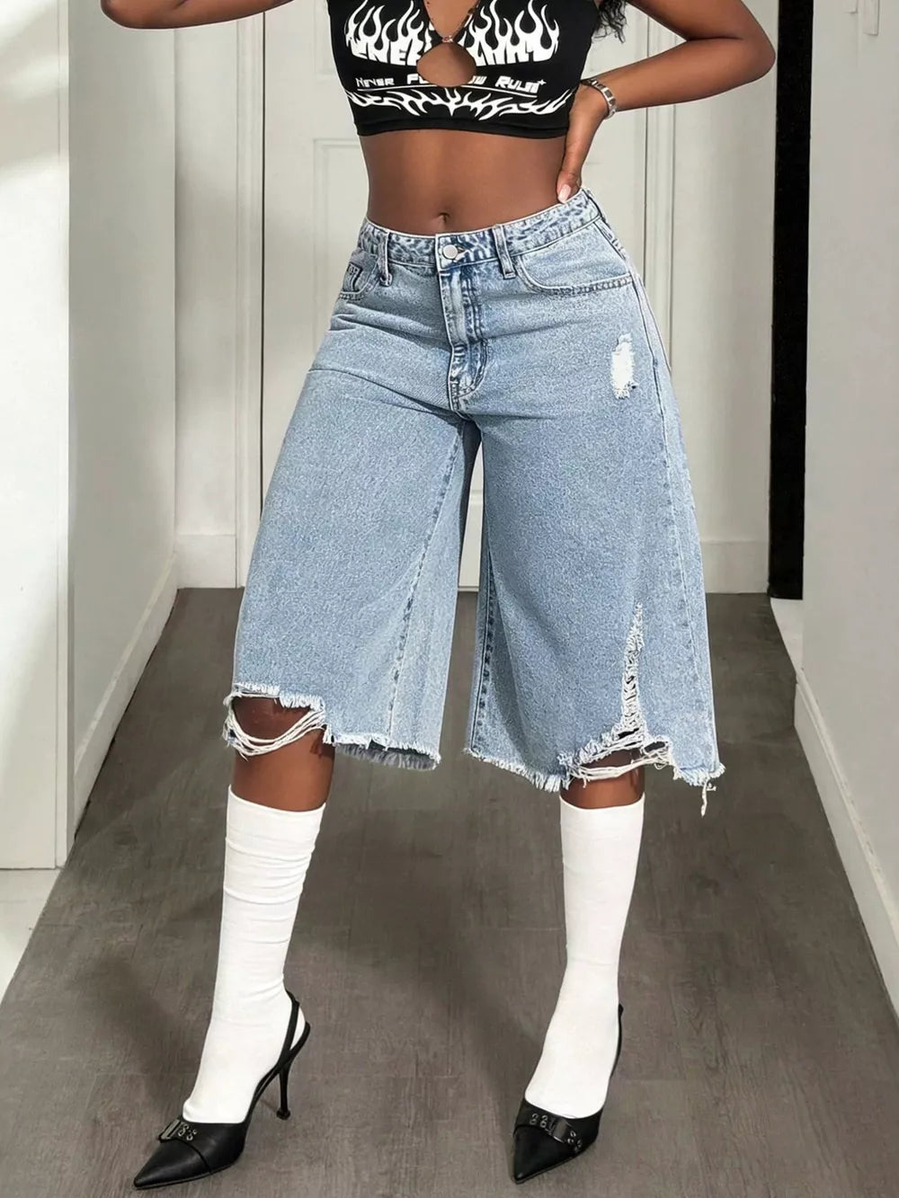 Distressed light wash denim wide-leg shorts with raw hem and ripped details.
