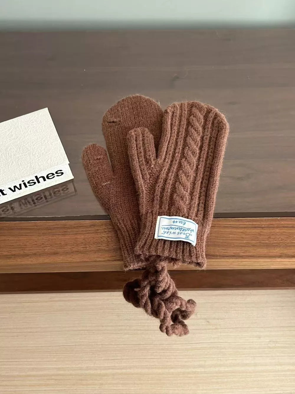 Brown cable knit acrylic gloves with a braided pattern and attached rope detail.