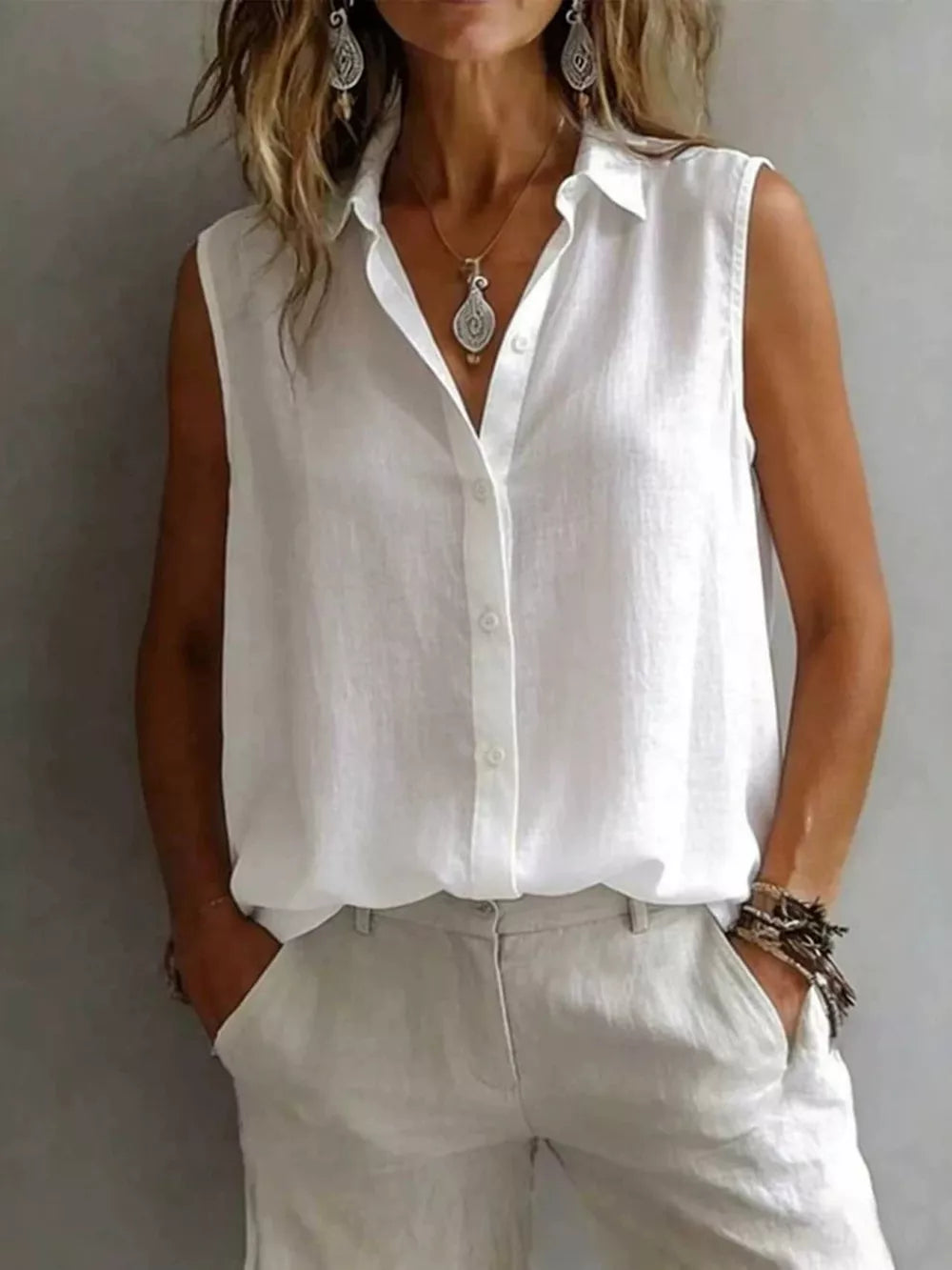 White sleeveless button-up shirt with a collared neckline and a relaxed fit.