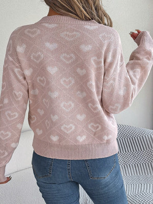 Blush pink acrylic V-neck knit sweater with allover white heart jacquard pattern.