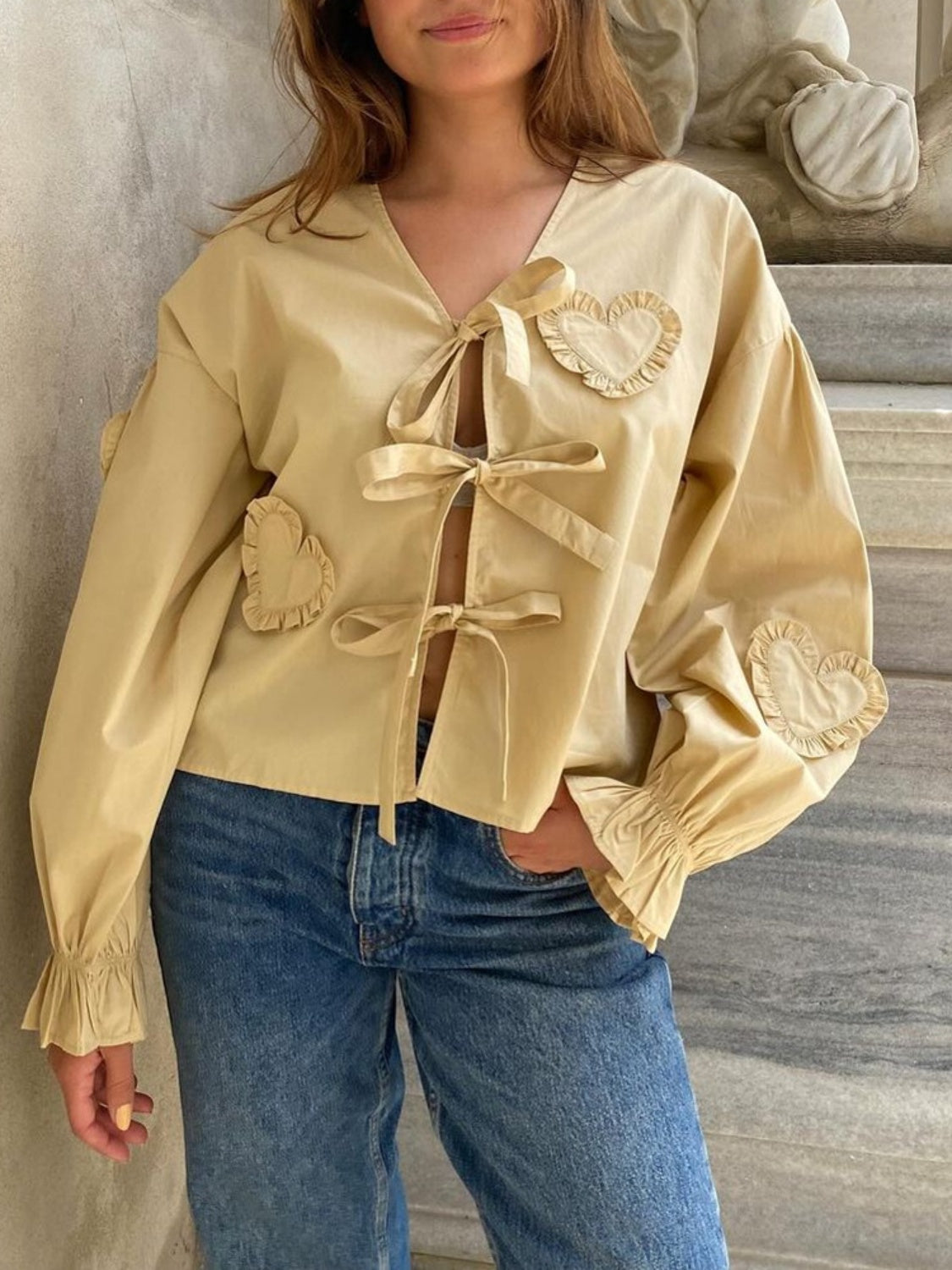 Pastel yellow blouse with heart appliqués and tie front, featuring ruffled cuffs and V-neck.