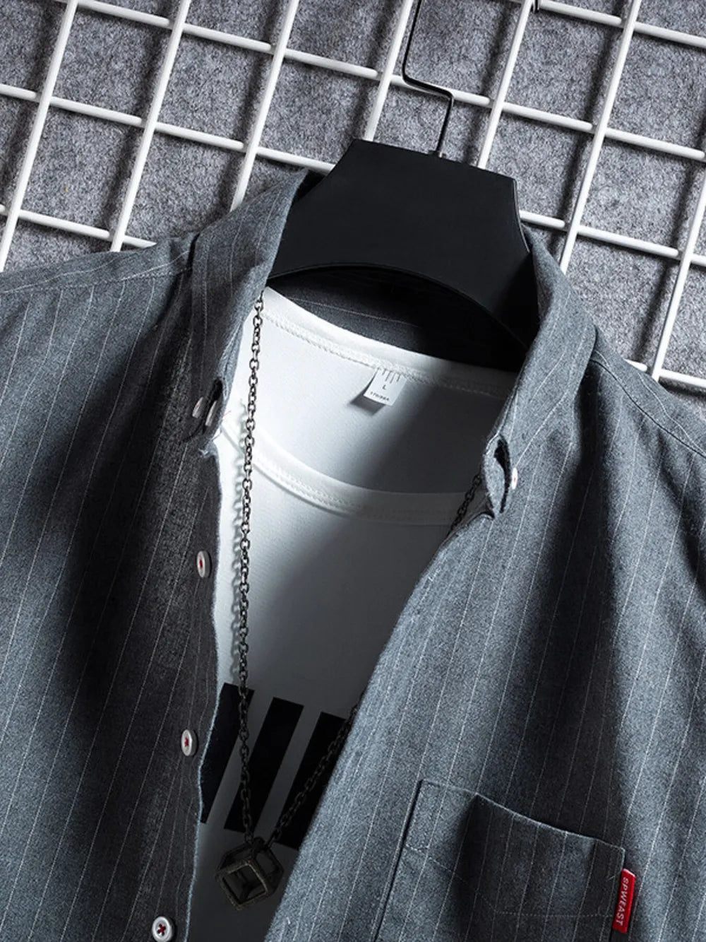 Grey striped short sleeve buttoned shirt with a white undershirt and chain necklace.