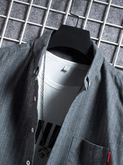 Grey striped short sleeve buttoned shirt with a white undershirt and chain necklace.