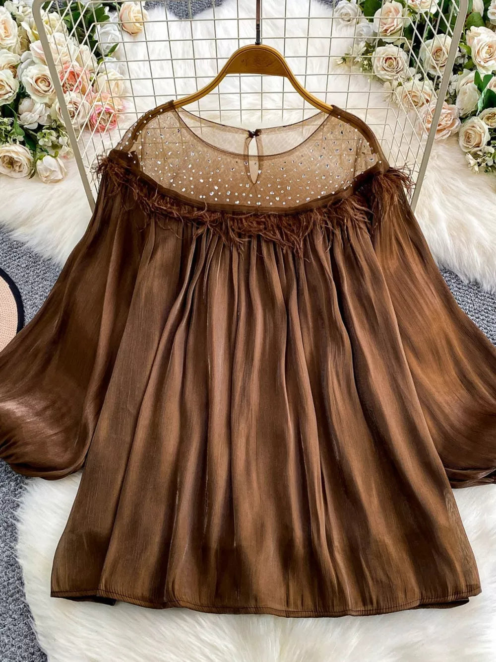 Brown sheer blouse with rhinestone embellishments on neckline and feather trim.