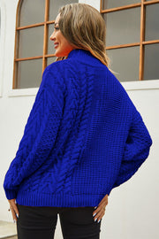 Royal blue cable-knit turtleneck sweater with voluminous silhouette and textured details.