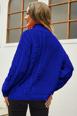 Royal blue cable-knit turtleneck sweater with voluminous silhouette and textured details.