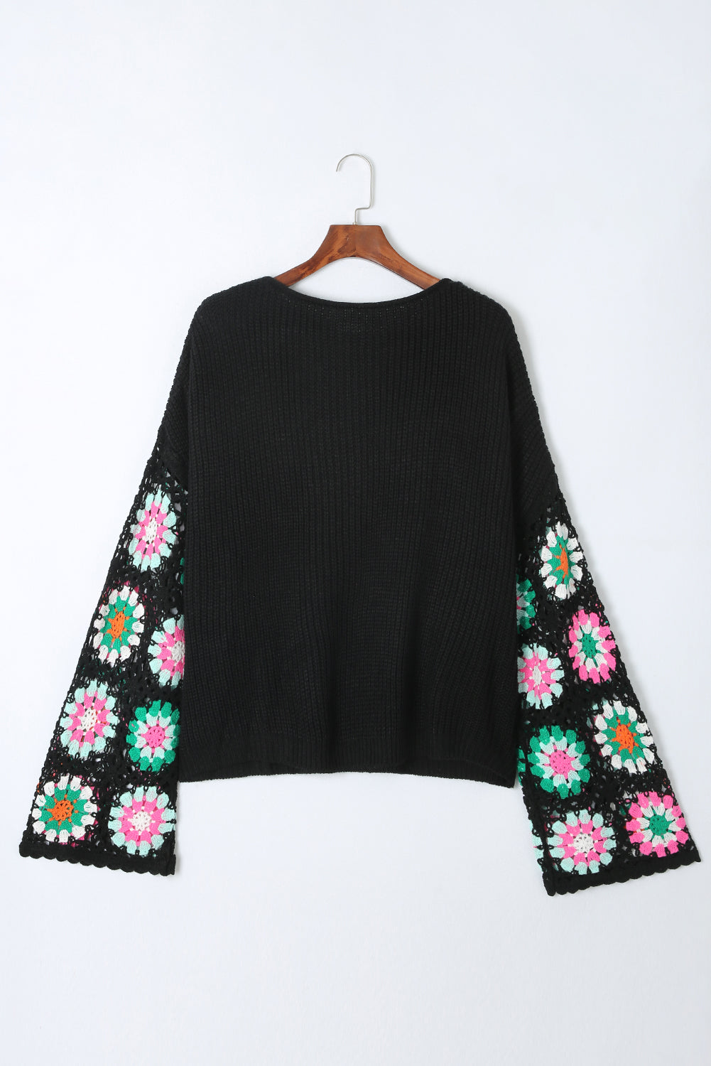Black knit pullover sweater with crochet granny square sleeves in pink, green, and white.