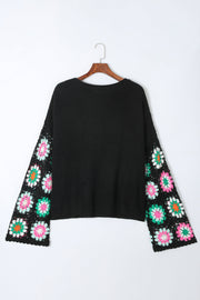 Black knit pullover sweater with crochet granny square sleeves in pink, green, and white.