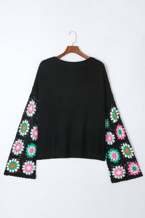 Black knit pullover sweater with crochet granny square sleeves in pink, green, and white.