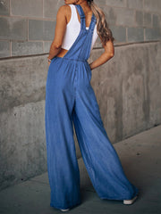 Denim palazzo jumpsuit in medium wash with wide legs and adjustable straps.