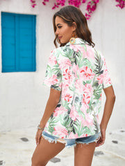 Tropical print camp collar shirt with pink flowers and green leaves, short sleeves, buttoned front.