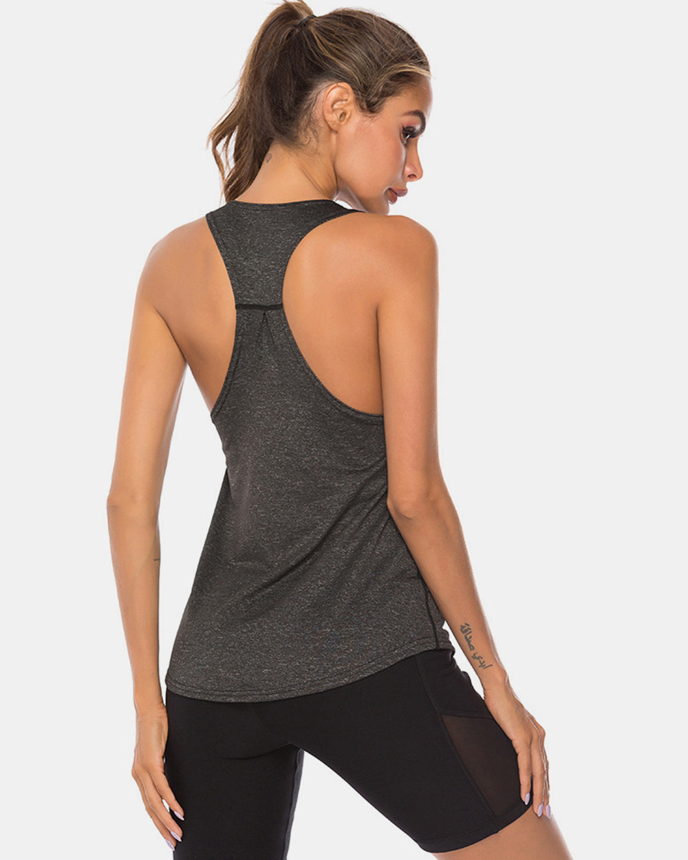 Racerback performance tank top in dark heather grey with a relaxed fit and curved hem.