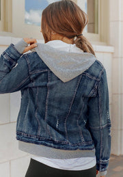 Dark blue denim jacket with grey hooded layer, distressed details, and ribbed cuffs.