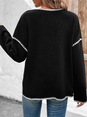 Black knit jacket with scalloped trim on neckline, sleeves, and hem.