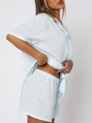 Light Blue striped pajama set with yellow floral print, collared button-up top and shorts.
