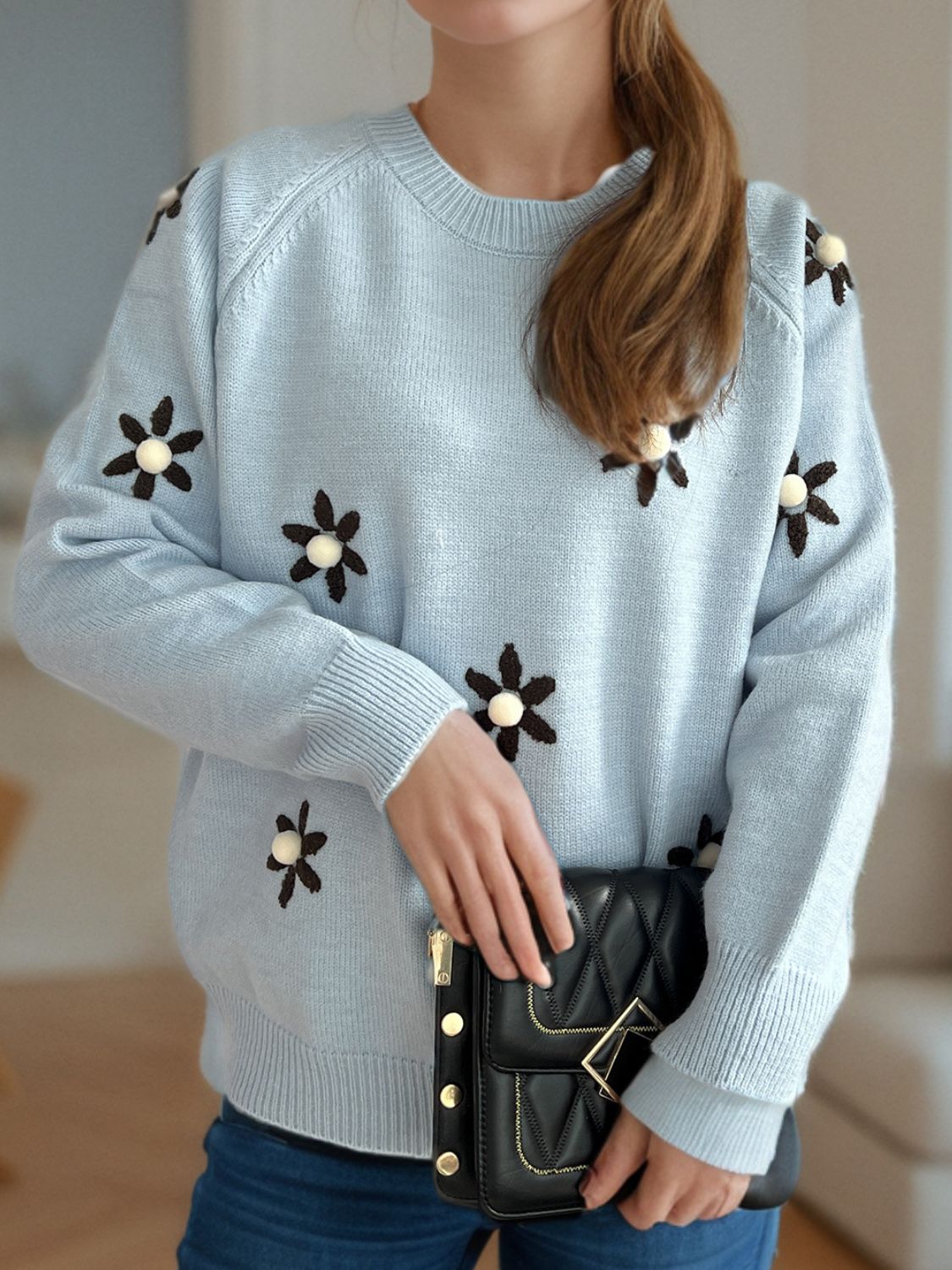 Pastel blue knit sweater with embroidered floral details and a crew neck.