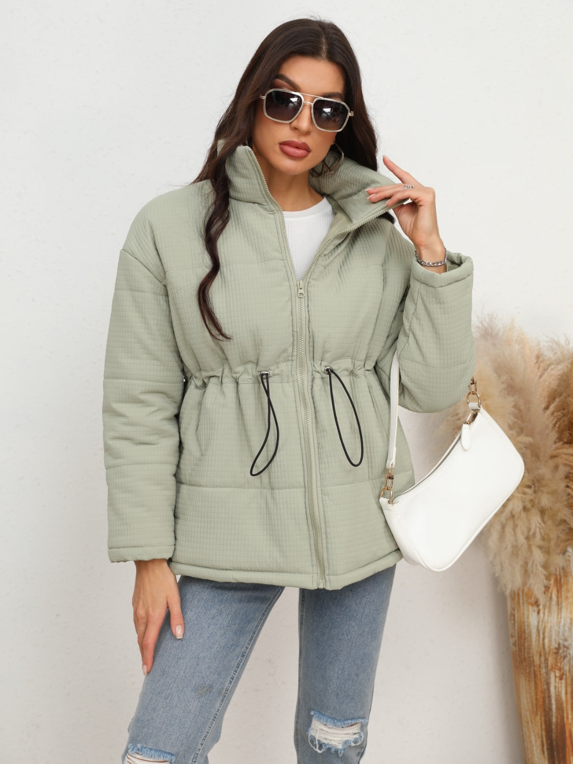 Light green textured puffer jacket with drawstring waist and zip-up front.