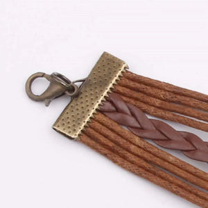 Brown layered braided charm bracelet with antique brass clasp and details.