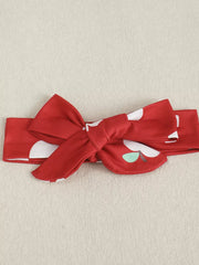 Red baby headband with white polka dots and apple print, featuring a bow.