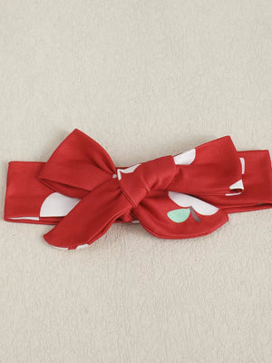 Red baby headband with white polka dots and apple print, featuring a bow.