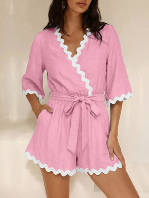 Pink wrap romper with white scalloped trim and 3/4 sleeves.