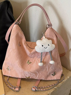 Blush pink shoulder bag with butterfly embellishments and a cloud charm.