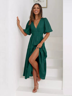 Dark green midi dress with puff sleeves, V-neck, cinched waist, tiered skirt, and thigh-high slit.