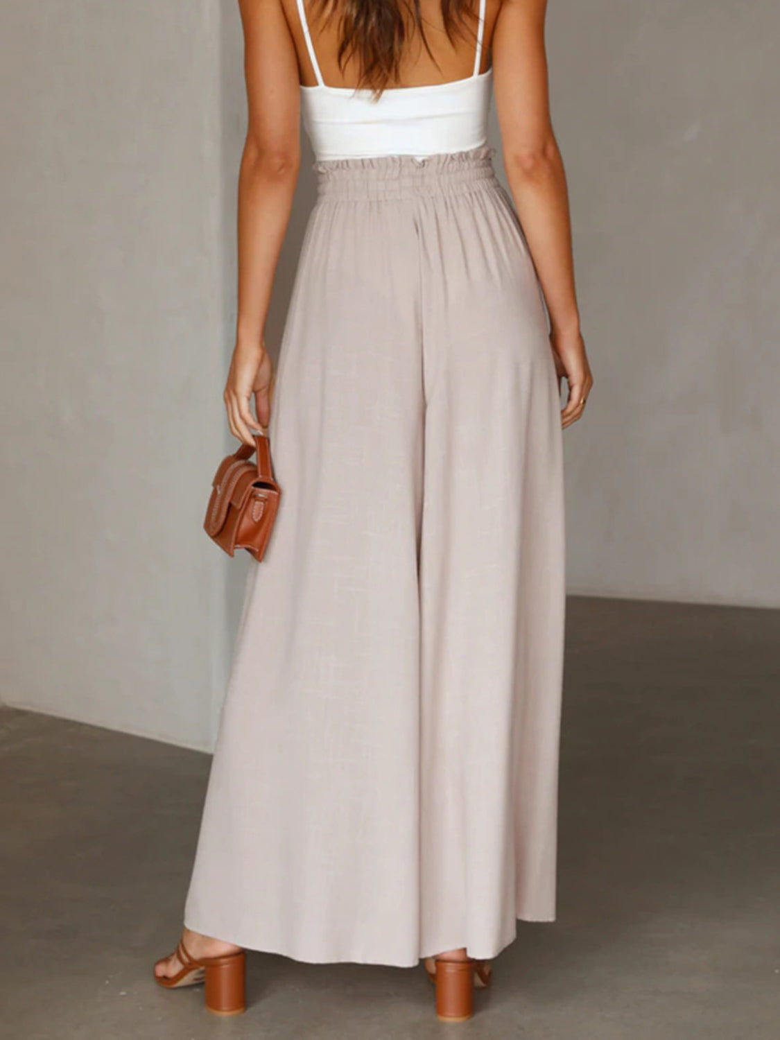Gathered waist wide-leg palazzo pants in eggshell, styled with a white tank and brown accessories.