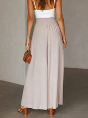Gathered waist wide-leg palazzo pants in eggshell, styled with a white tank and brown accessories.