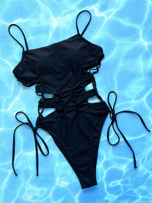 Black one-piece swimsuit with strappy cutouts and adjustable side ties.