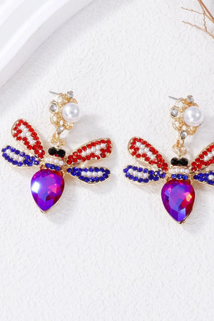 Jeweled dragonfly chandelier earrings with red, white, and blue stones and a purple gem body.