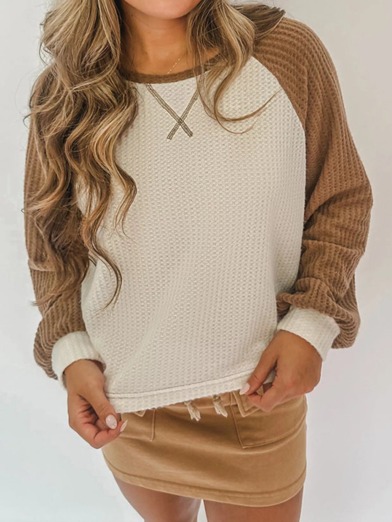 Beige waffle knit raglan sleeve top with contrast sleeves and X detail at neckline.