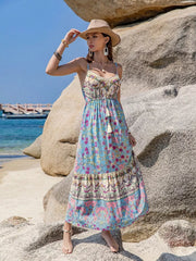 Maxi dress with vibrant floral border print, tassels, and spaghetti straps.