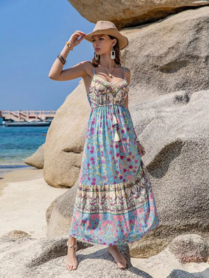 Maxi dress with vibrant floral border print, tassels, and spaghetti straps.