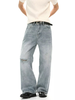 Light wash distressed denim wide-leg jeans with a ripped knee detail.