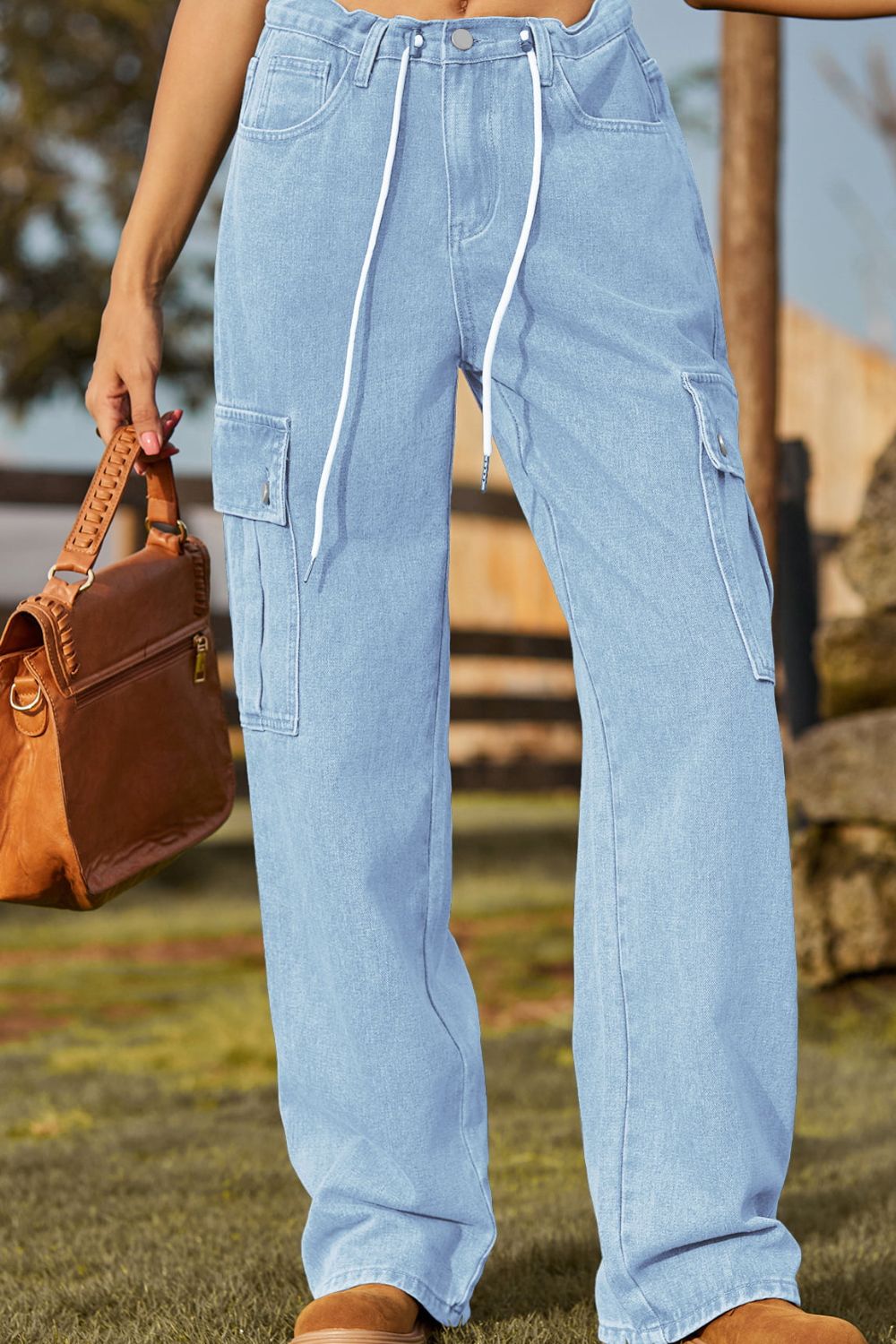 Light wash denim cargo pants with drawstring waist and button flap pockets.