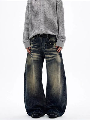 Men's vintage wash wide leg jeans with distressed detailing and a belted waist.
