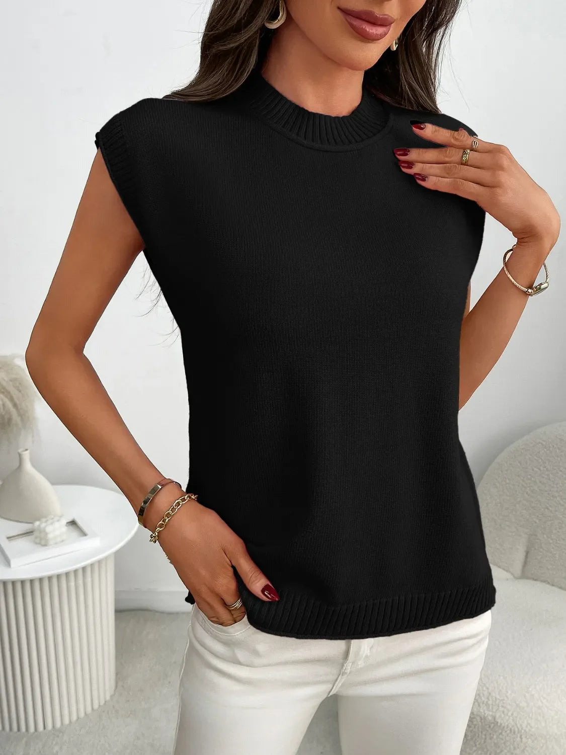 Black ribbed knit sleeveless mock neck top with gold bracelets.